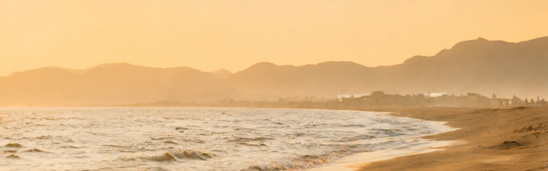 A warm, quiet shoreline beneath a coastal mountain ridge